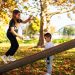 Two children enjoy a playful afternoon on a seesaw surrounded by vibrant autumn colors in the park.